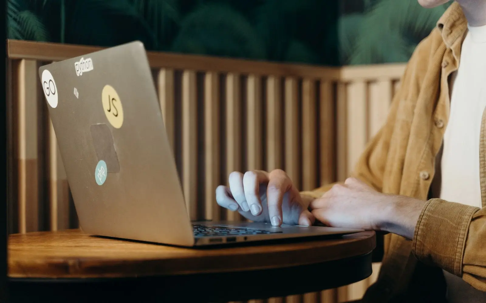 Hands typing on a laptop at a café table.